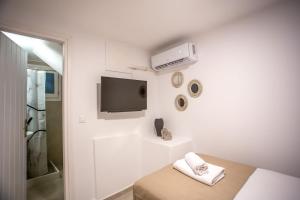 a white room with a bed and a tv at Magic Holidays 222 in Mýkonos City