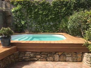 a swimming pool in a garden with a wooden deck at Les lauriers du loft in Pazayac