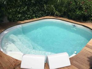 a small swimming pool with two white chairs in it at Les lauriers du loft in Pazayac