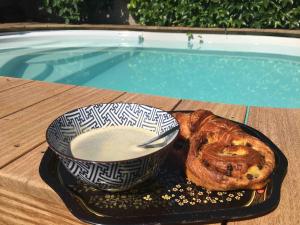 a plate of bread and a bowl of milk next to a pool at Les lauriers du loft in Pazayac
