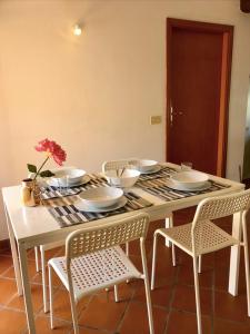 een witte tafel met stoelen, borden en bloemen erop bij Mansarda la Graziosa in Rimini