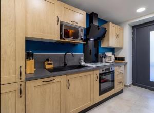 a kitchen with wooden cabinets and a microwave at "Le Glandon"- Parenthèse de charme in Saint Avre la Chambre