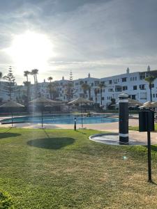 a person standing near a swimming pool with umbrellas at Appartement marina beach f5 n6 in M'diq