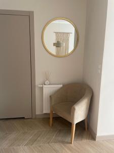 Cette chambre comprend une chaise et un miroir mural. dans l'établissement Apartament Sikorki, à Sianożęty