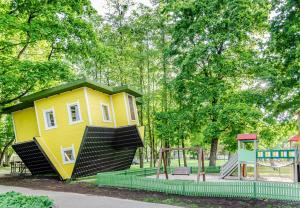 een klein geel huisje in een park met een speeltuin bij Nemunas A respite Studio 8 in Druskininkai +9 foto's