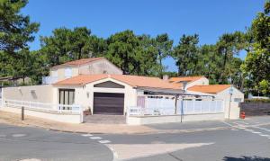 ein weißes Haus mit einer Garage und einem Zaun in der Unterkunft Maison Princesse in La Tranche-sur-Mer