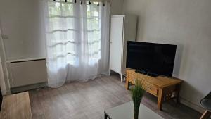 a living room with a flat screen tv and a table at Le Gîte Le Ladignacois - Cosy, calme & indépendant - 2 à 4 pers in Ladignac-le-Long
