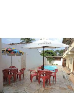 2 Tische und Stühle mit Sonnenschirm auf der Terrasse in der Unterkunft Hospedagem Econômica Flor de Maria 2 in Caraguatatuba