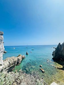 a beach with rocks and the ocean with boats in it at Acquario - Immobilevante in Ponza