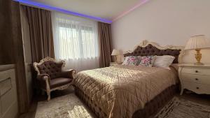 ein Schlafzimmer mit einem Bett, einem Stuhl und einem Fenster in der Unterkunft Mara Stefania Apart Hotel Deluxe in Oradea