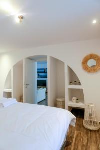a bedroom with a white bed and a mirror at Magic Holidays 444 in Mýkonos City