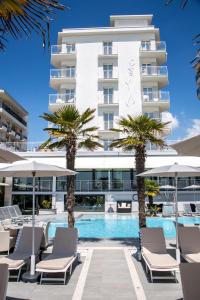 a hotel with a swimming pool and palm trees at Hotel Sayonara in Lido di Jesolo
