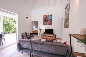 Una sala de estar con un sofá y un televisor. en Villa Trezel - Saint-François, en Saint-François