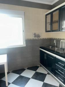 a kitchen with black cabinets and a checkered floor at Appartement Belyouneche in Belyounech 