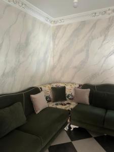 a living room with a couch and a marble wall at Appartement Belyouneche in Belyounech 