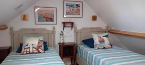 une chambre avec deux lits et deux tableaux au mur dans l'établissement La Goélette Beau duplex A 150 m du centre ville et 400m de la plage de l'écluse, à Dinard
