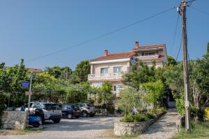 Un edificio con coches aparcados en un estacionamiento. en Apartments Vesna, en Rab