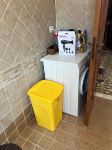 a washing machine and a yellow trash can in a bathroom at Casa sul mare in Vibo Valentia Marina