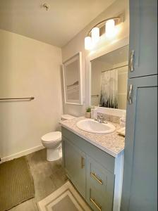 een badkamer met een wastafel, een toilet en een spiegel bij City Center Olive Grove in Kamloops