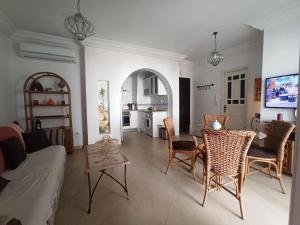 a living room with a couch and a table and chairs at appartement avec piscine in Houmt Souk