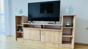 TV en un centro de entretenimiento de madera en una sala de estar en ASTORIA II Apartment 23 One Bedroom, en Elenite