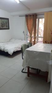 a room with two beds and a table and a window at דירת חדר זוגית in Safed