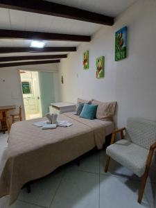 a bedroom with a large bed and a chair at Suíte Amazônia in Bombinhas +17 photos