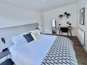 a bedroom with a large white bed and a desk at Kingfisher - Luxurious Off-Grid Eco Cabin with Riverviews in Market Drayton