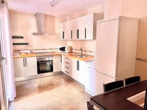 a small kitchen with white cabinets and a sink at Venezuela 20-22 in La Línea de la Concepción