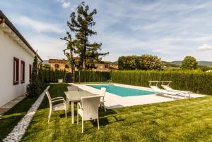 ピストイアにあるPodere Villa Olmoのテーブルと椅子のある裏庭、スイミングプールを提供しています。
