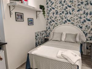 Cama pequeña en habitación con papel pintado azul y blanco en DOMUS ULIVI LUXURY ROOMS Moresca, en Catania 17 fotos más