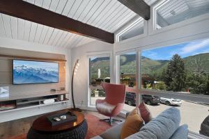 a living room with a couch and a tv and mountains at Shadow Mountain 03 in Aspen