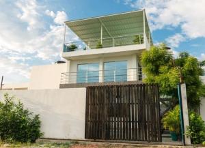 a white house with a balcony on top of it at Cabaña Pandu in Playa Bello Horizonte