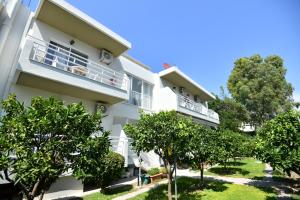 a white building with trees in front of it at Casa al'tati studios in Ialyssos