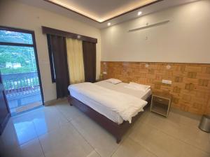 a bedroom with a bed and a large window at Hotel Kailash in Harsil +18 photos