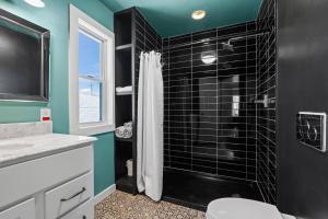a bathroom with a shower with a black tile wall at Whole House in Walker's Point in Milwaukee +15 photos