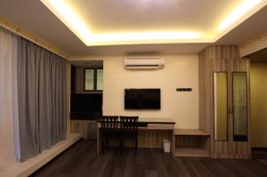 sala de estar con TV, mesa y sillas en Shamrock Guest House, en Ipoh