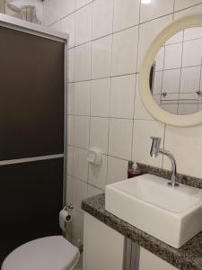 a bathroom with a sink and a toilet and a mirror at Murilo House - Apart-hotel completo e privativo in São José +28 photos