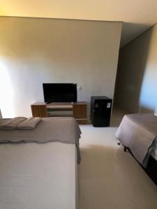 a bedroom with two beds and a flat screen tv at Hotel Araguaia Exclusive in Aruanã +8 photos
