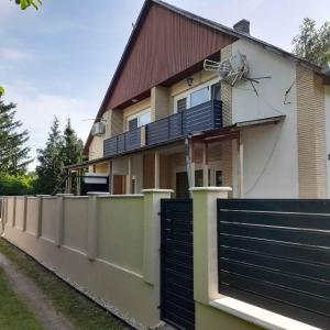ein Haus mit einem schwarzen Tor und einem Zaun in der Unterkunft Holiday Homes in Balatonmariafürdo 48114 in Balatonmáriafürdő + 8 Fotos