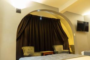 a room with a bed and two chairs and a window at Hotel El Arroyo in Caracas