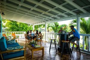 a group of people sitting at a bar on a porch at The Sea Glass Inn in Placencia Village