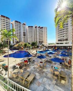 a pool with chairs and tables and blue umbrellas at Wyndhan Royal Hotel Resort Olimpia in Olímpia