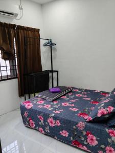 a bedroom with a bed with a floral comforter at Homestay Masjid Seberang Marang in Marang