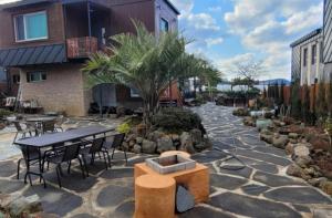 a stone patio with a table and chairs and trees at Aewol Aurora Pension in Jeju