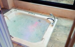 a bath tub filled with water with a faucet at NJ Pool Villa in Hoengseong