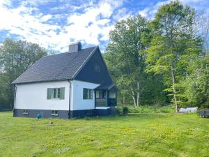 a white house with a black roof in a field at 5 person holiday home in Stehag in Stehag