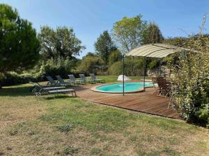 a deck with chairs and an umbrella next to a pool at Villa in France with Private Pool & Garden in Chalais