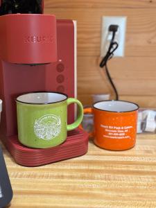 two cups sitting on plates next to a coffee maker at Ozark RV Park and Cabins in Mountain View +1 photo