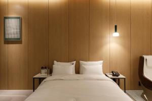 a bedroom with a bed with white sheets and a sink at Just Sleep Hotel Suite Cheonan Station in Cheonan